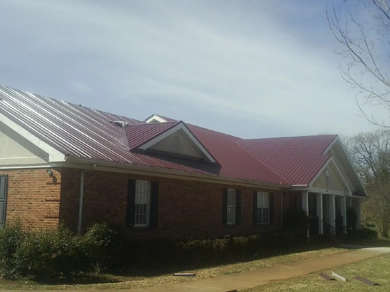 Red metal roof with gabled entries on a long brick building in Waldron